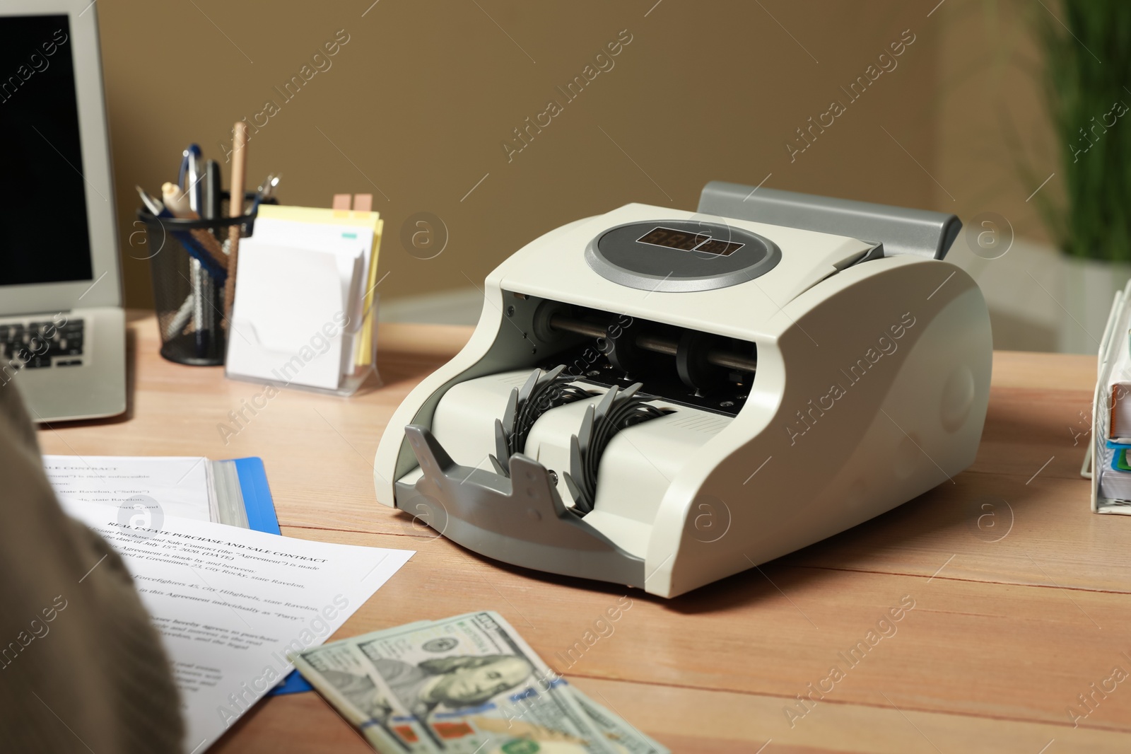 Photo of Modern banknote counter on wooden table indoors