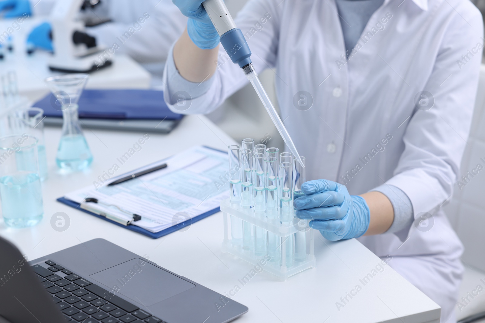 Photo of Scientist dripping sample into test tube in laboratory, closeup