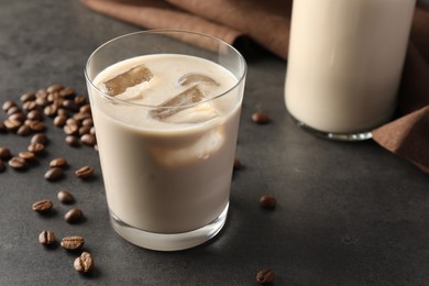 Coffee cream liqueur in glass and beans on grey table, closeup