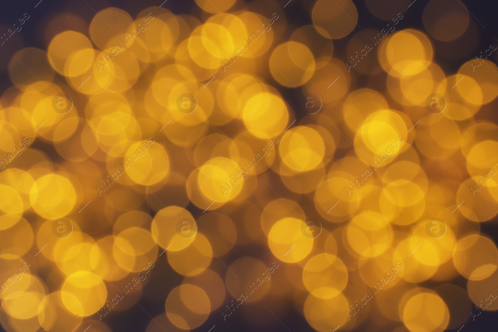 Photo of Blurred view of glowing Christmas lights on violet background