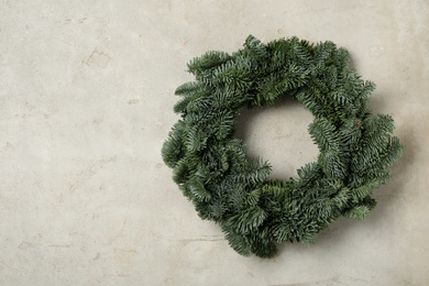 Photo of Christmas wreath made of fir tree branches on light grey background, space for text