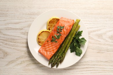 Photo of Tasty grilled salmon with asparagus and lemon on white wooden table, top view