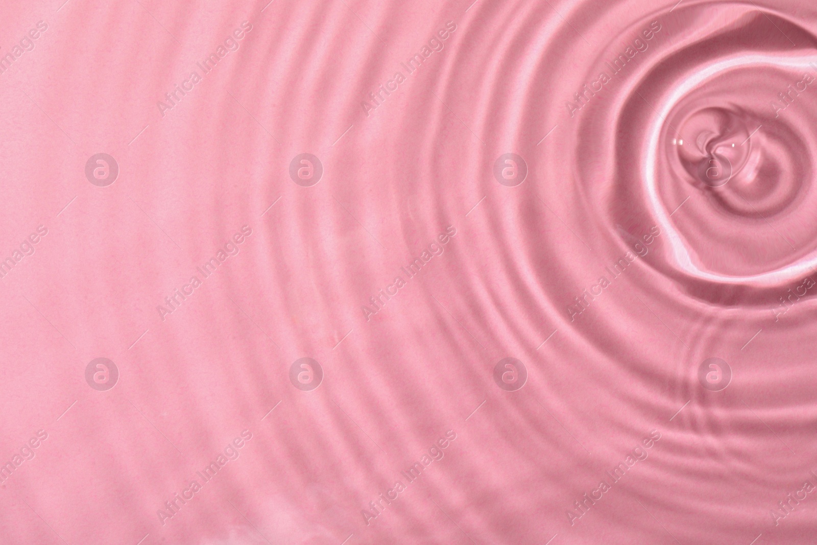 Photo of Closeup view of water with rippled surface on pink background