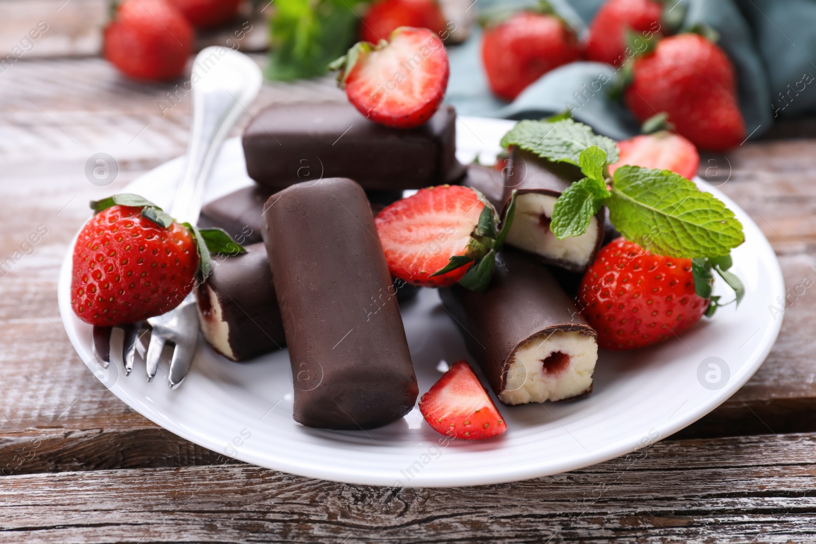 Photo of Delicious glazed curd snacks with fresh strawberries and mint on wooden table