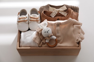 Photo of Wooden crate with children's clothes, shoes and toy on white table