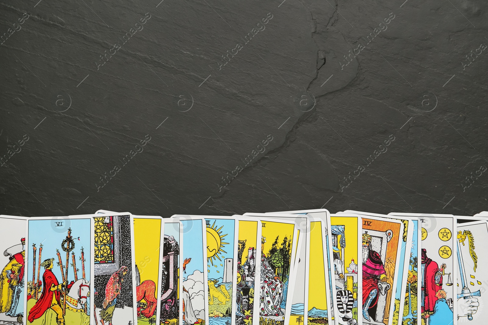 Photo of Tarot cards on black table, top view. Space for text