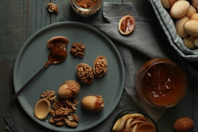 Photo of Freshly baked homemade walnut shaped cookies with nuts and boiled condensed milk on wooden table, flat lay