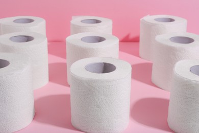 Photo of Many soft toilet paper rolls on pink background, closeup