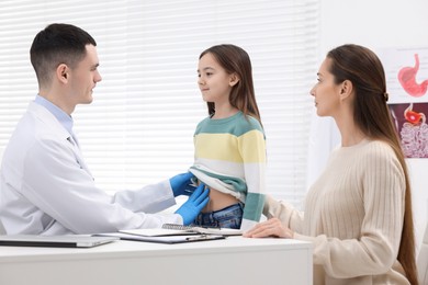 Photo of Gastroenterologist examining girl with stomach ache in clinic