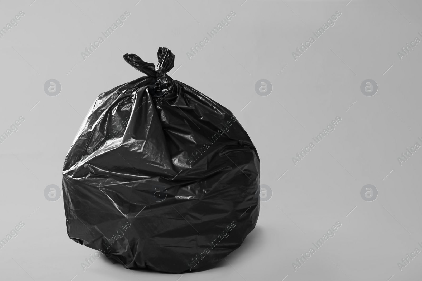 Photo of Trash bag full of garbage on grey background. Space for text