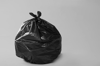 Photo of Trash bag full of garbage on grey background. Space for text