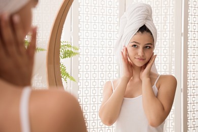Beautiful teenage girl with towel near mirror in bathroom