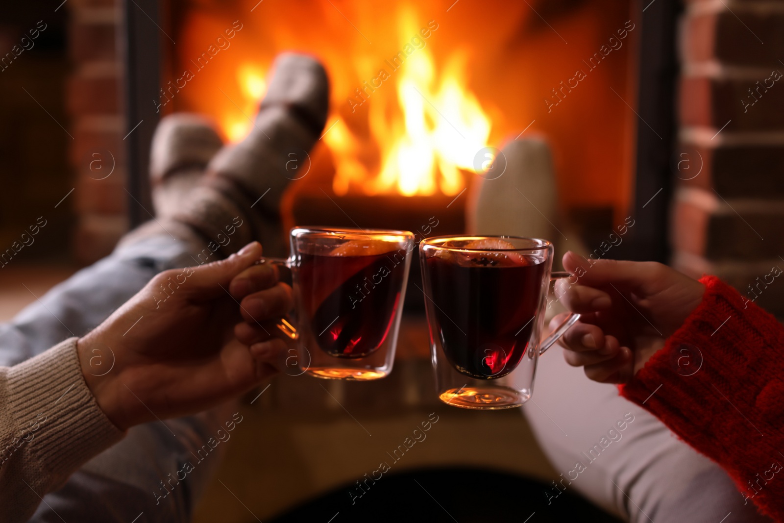 Photo of Couple with mulled wine near fireplace indoors, closeup. Winter vacation