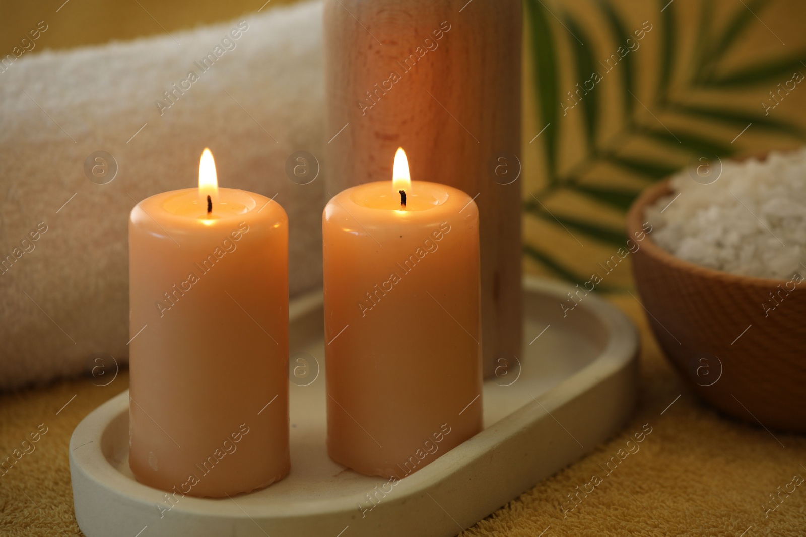 Photo of Spa composition with burning candles on soft yellow fabric