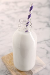 Photo of Bottle of tasty milk on white table, closeup