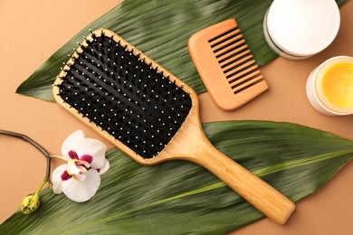 Photo of Flat lay composition with wooden hairbrush and comb on light brown background