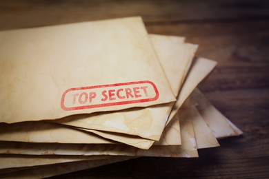 Image of Top Secret stamp. Stacked old letters on wooden table, closeup