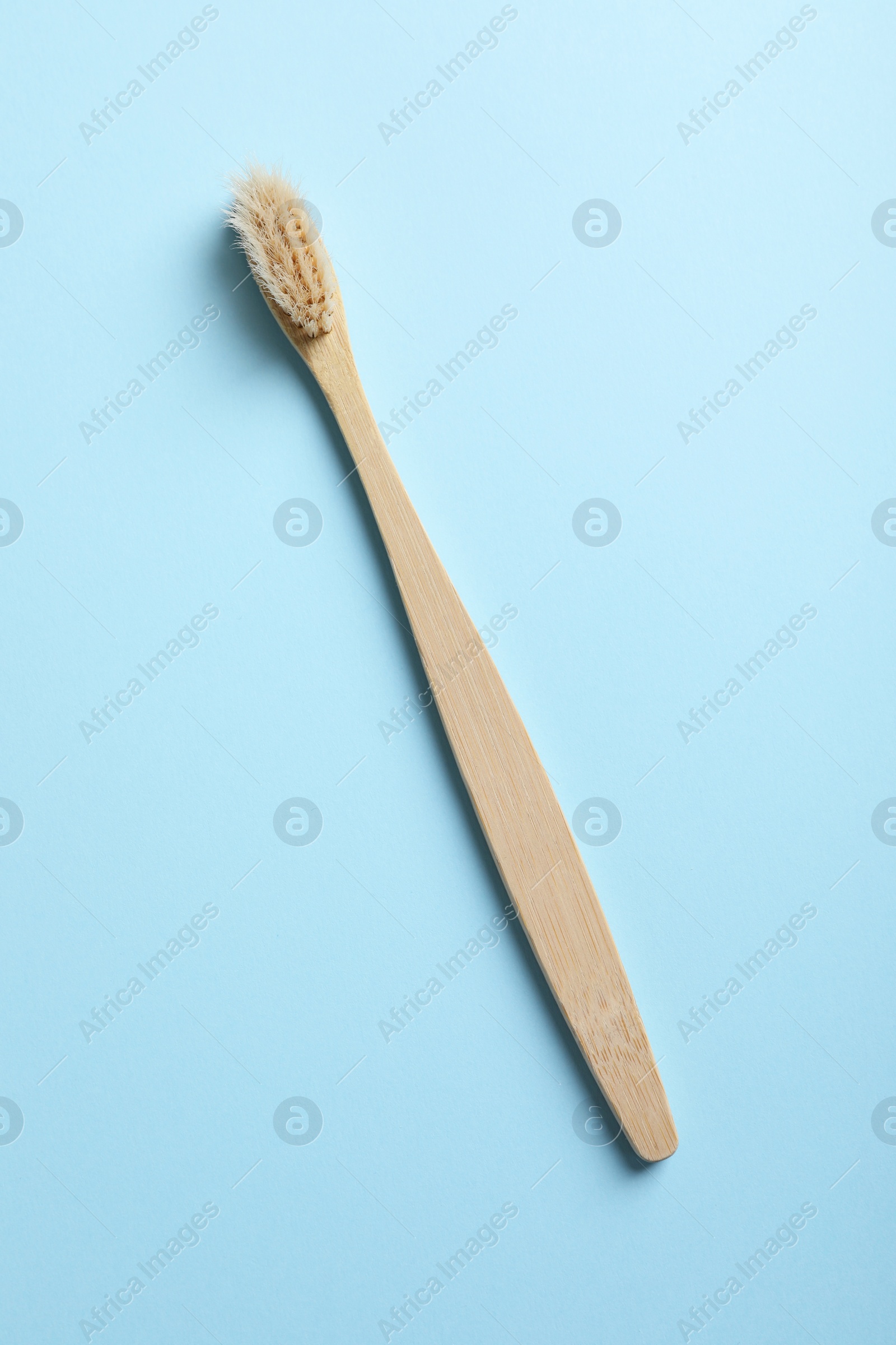 Photo of One bamboo toothbrush on light blue background, top view