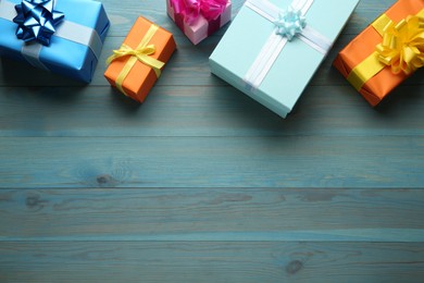 Many colorful gift boxes on light blue wooden table, flat lay. Space for text