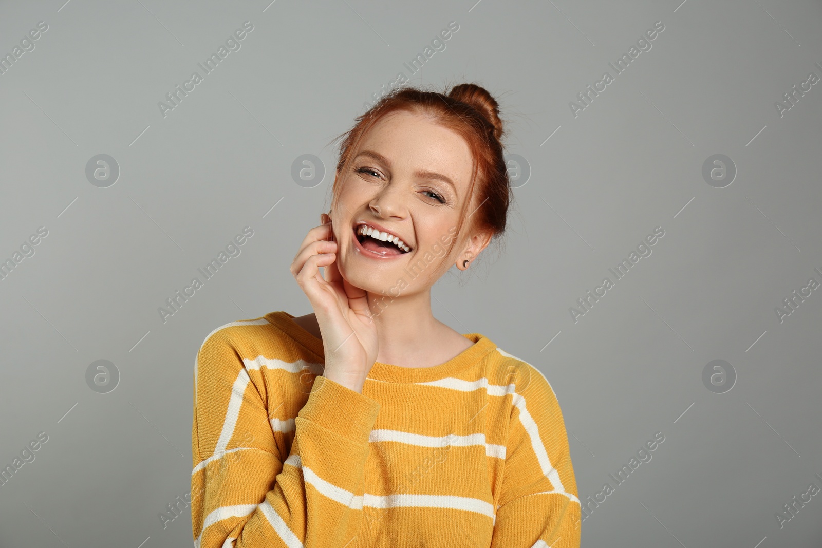 Photo of Candid portrait of happy red haired woman with charming smile on grey background