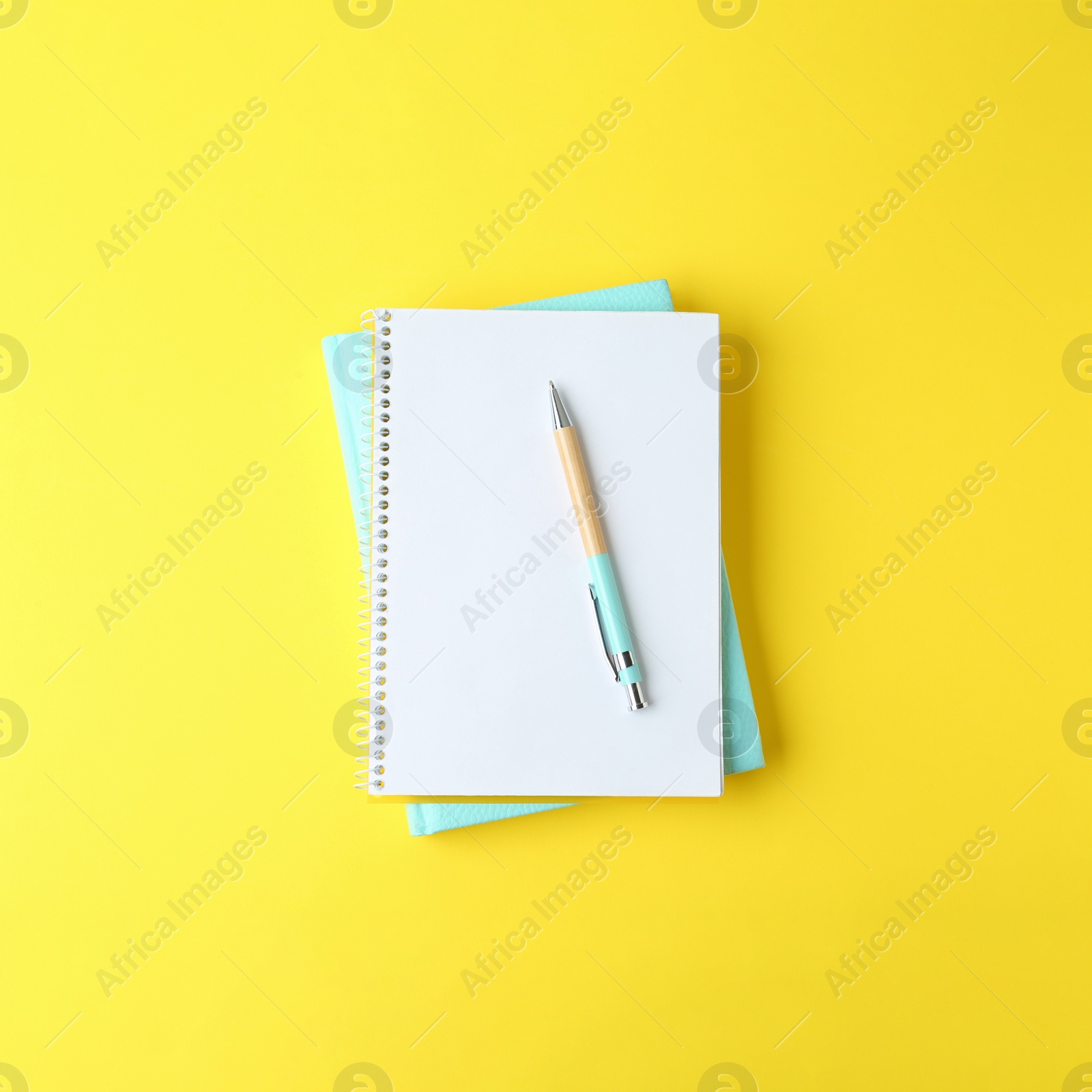 Image of Notebooks and pen on yellow background, top view