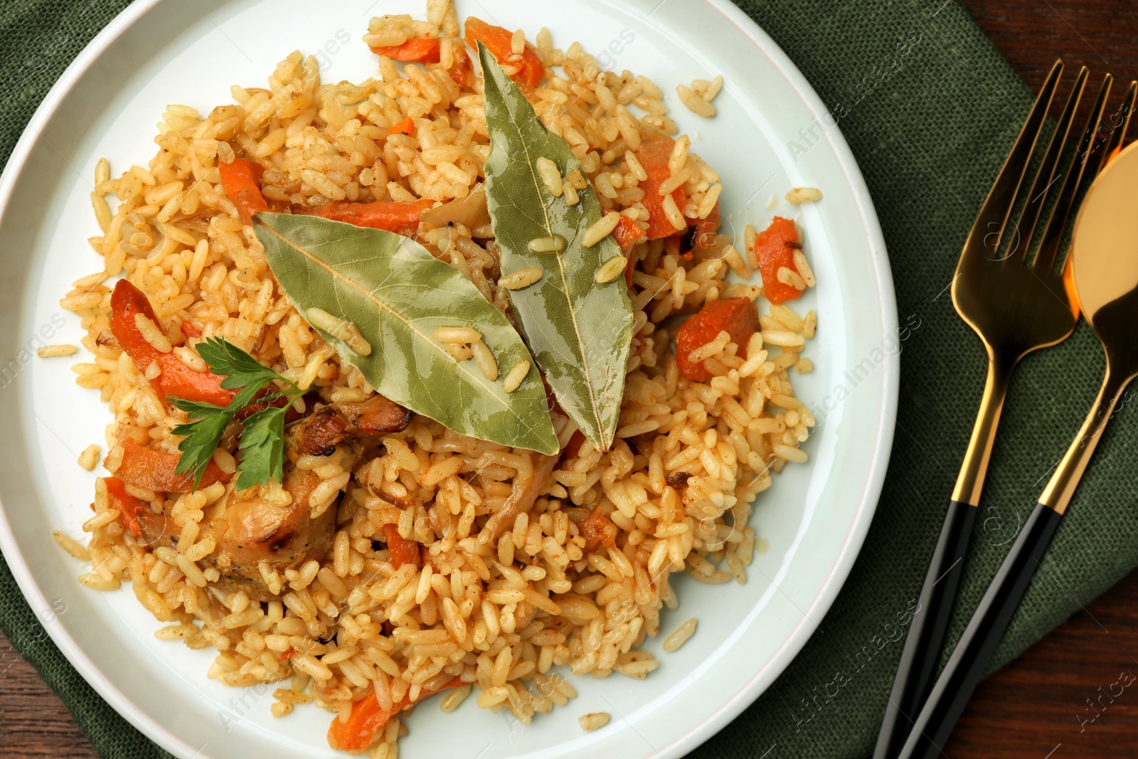 Photo of Delicious pilaf and bay leaves served on table, flat lay