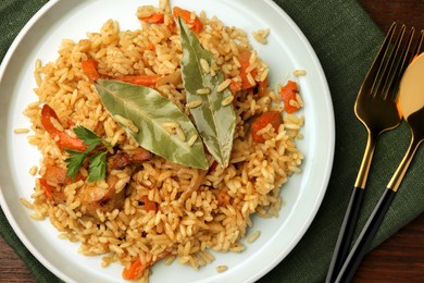 Delicious pilaf and bay leaves served on table, flat lay