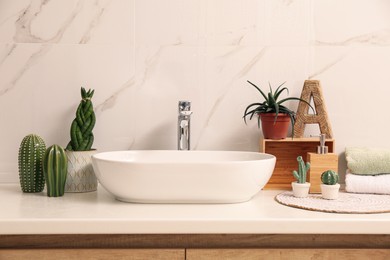 Photo of Vessel sink and different houseplants on countertop in bathroom