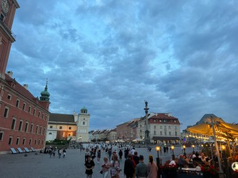 Photo of WARSAW, POLAND - JULY 15, 2022: View of crowded Old Town Market Place under cloudy sky in evening