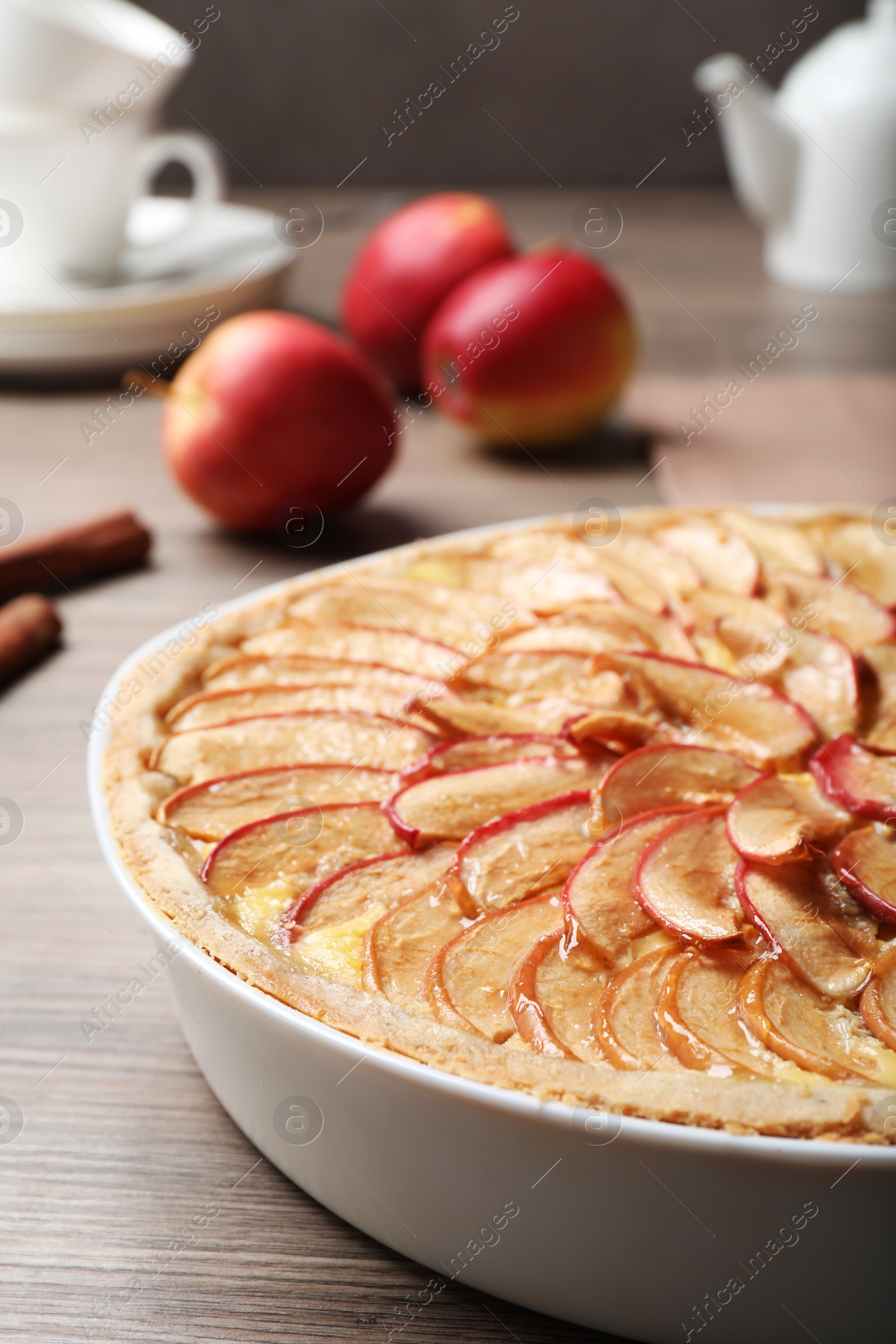 Photo of Tasty apple pie in baking dish on wooden table, closeup