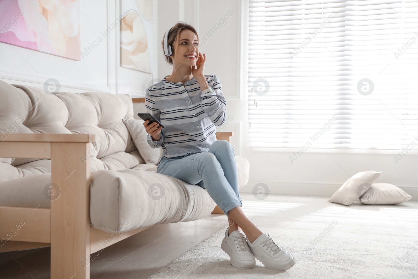 Photo of Young woman listening to music at home