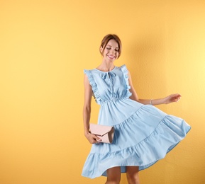 Portrait of young woman in stylish outfit with purse on color background