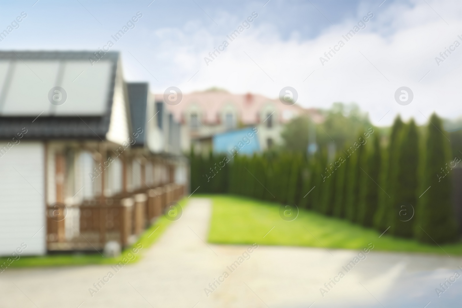 Photo of Blurred view of beautiful houses and green garden on sunny day