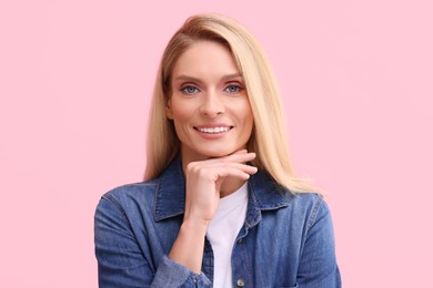 Photo of Portrait of smiling middle aged woman with blonde hair on pink background