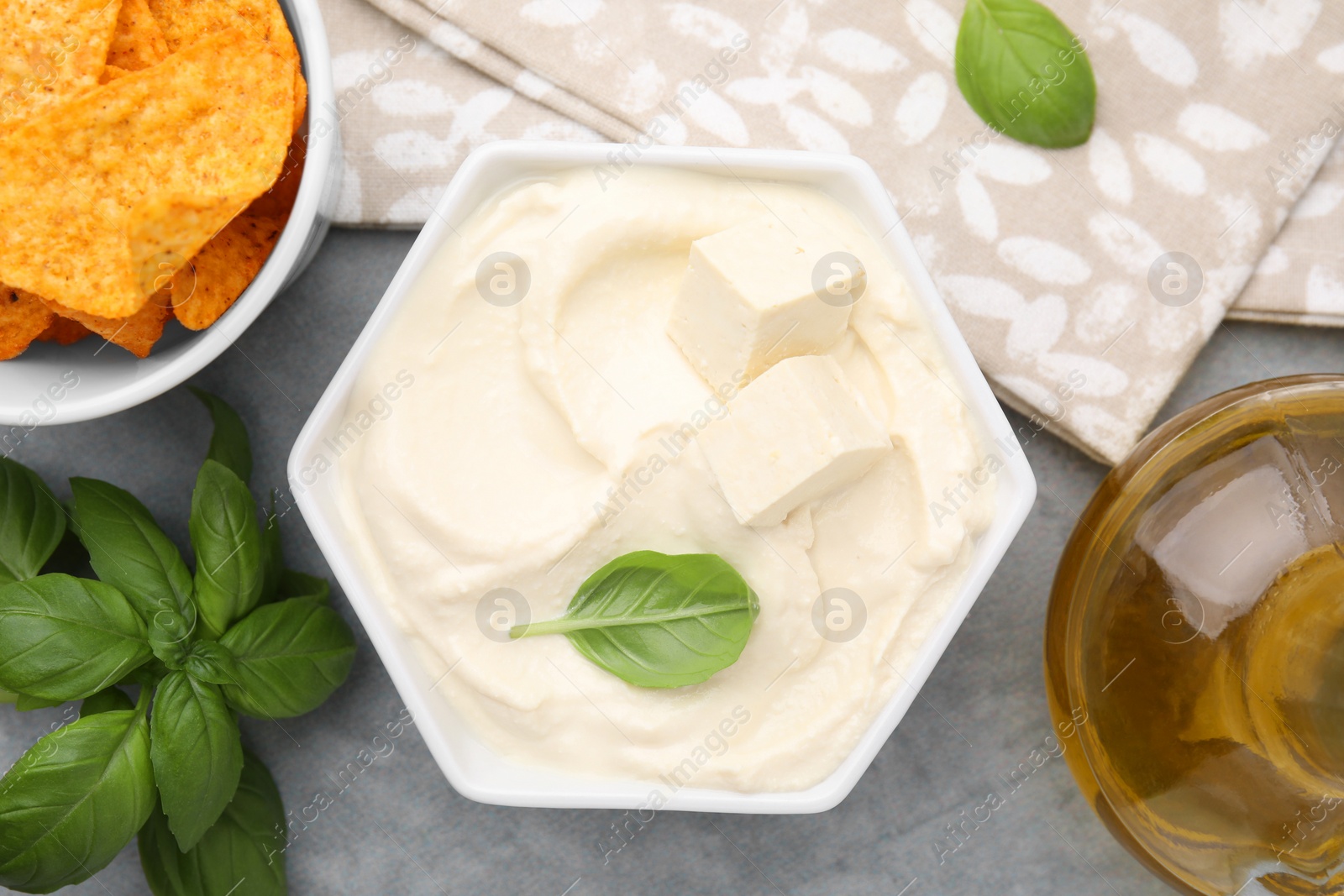 Photo of Delicious tofu sauce served with nachos chips on grey table, flat lay