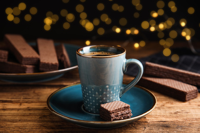 Photo of Delicious wafer and cup of coffee on wooden table