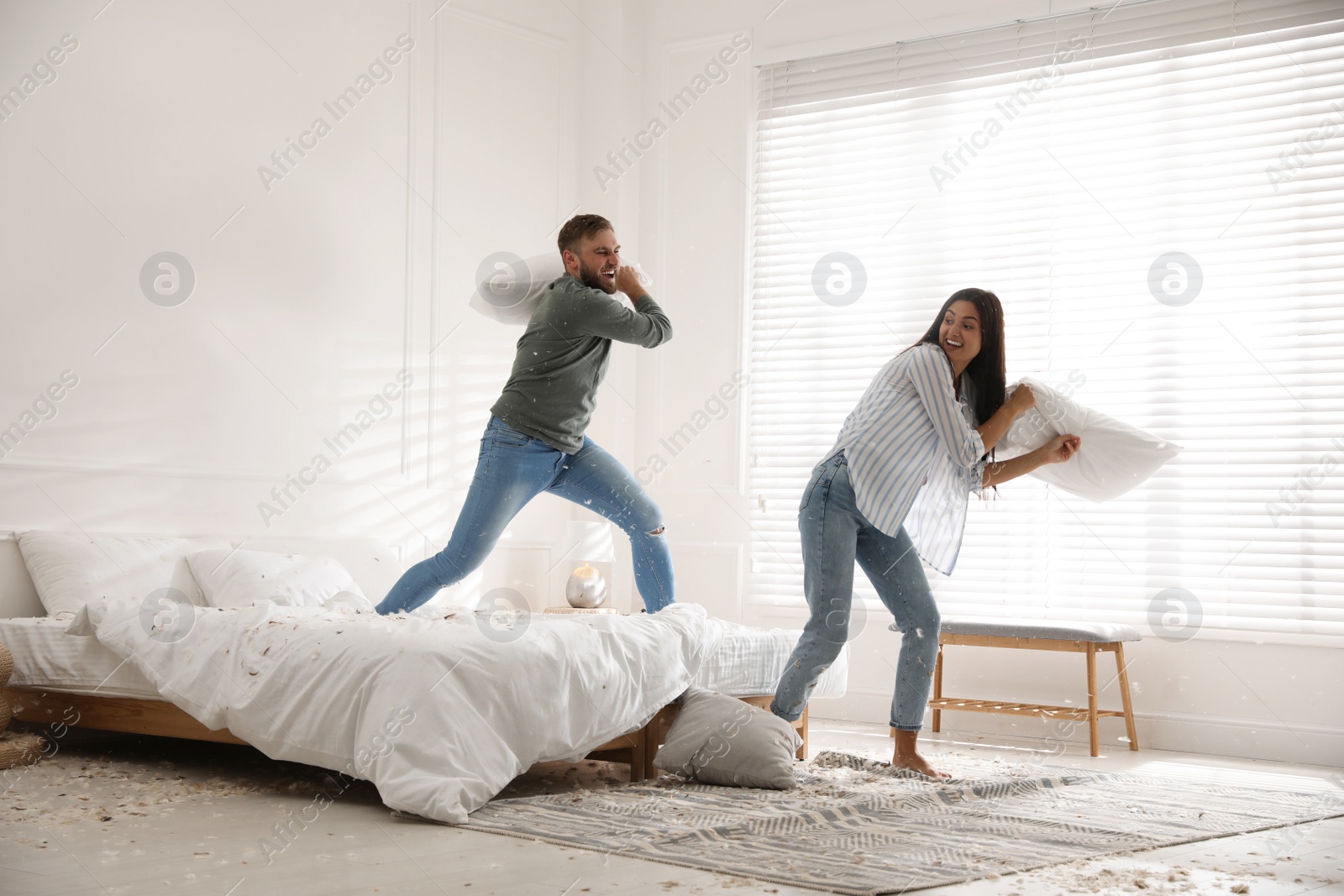 Photo of Happy young couple having fun pillow fight in bedroom