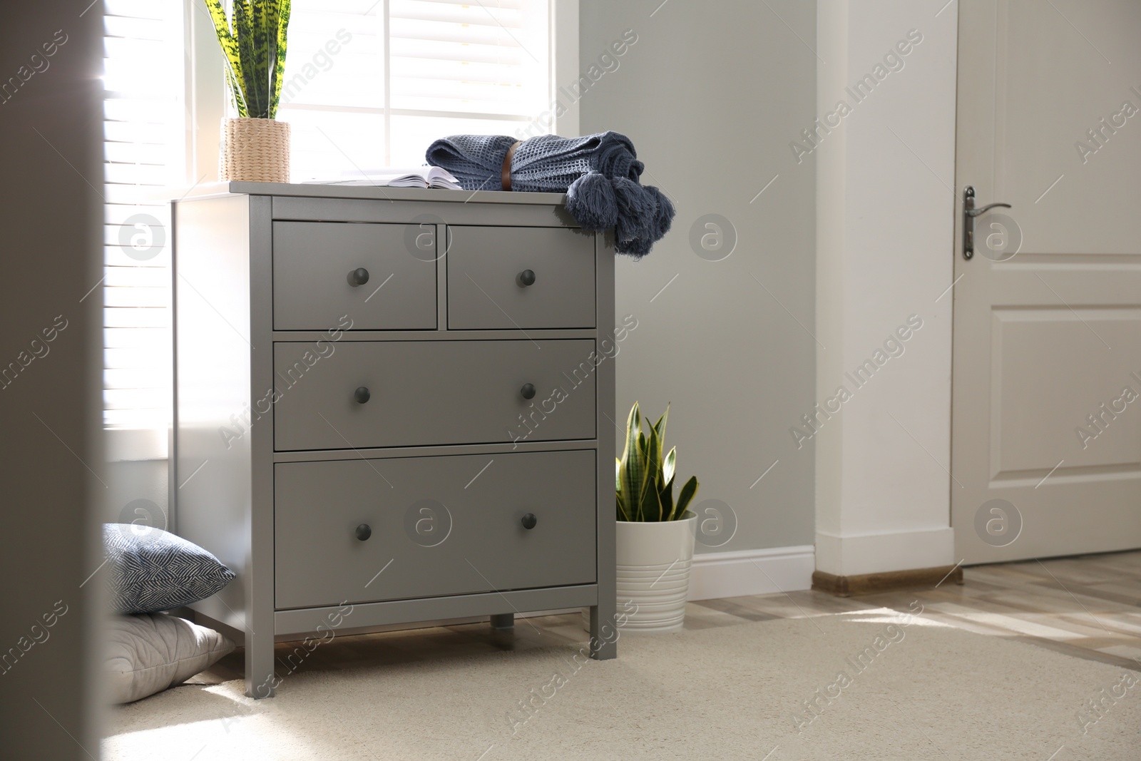 Photo of Grey chest of drawers near window in stylish room interior