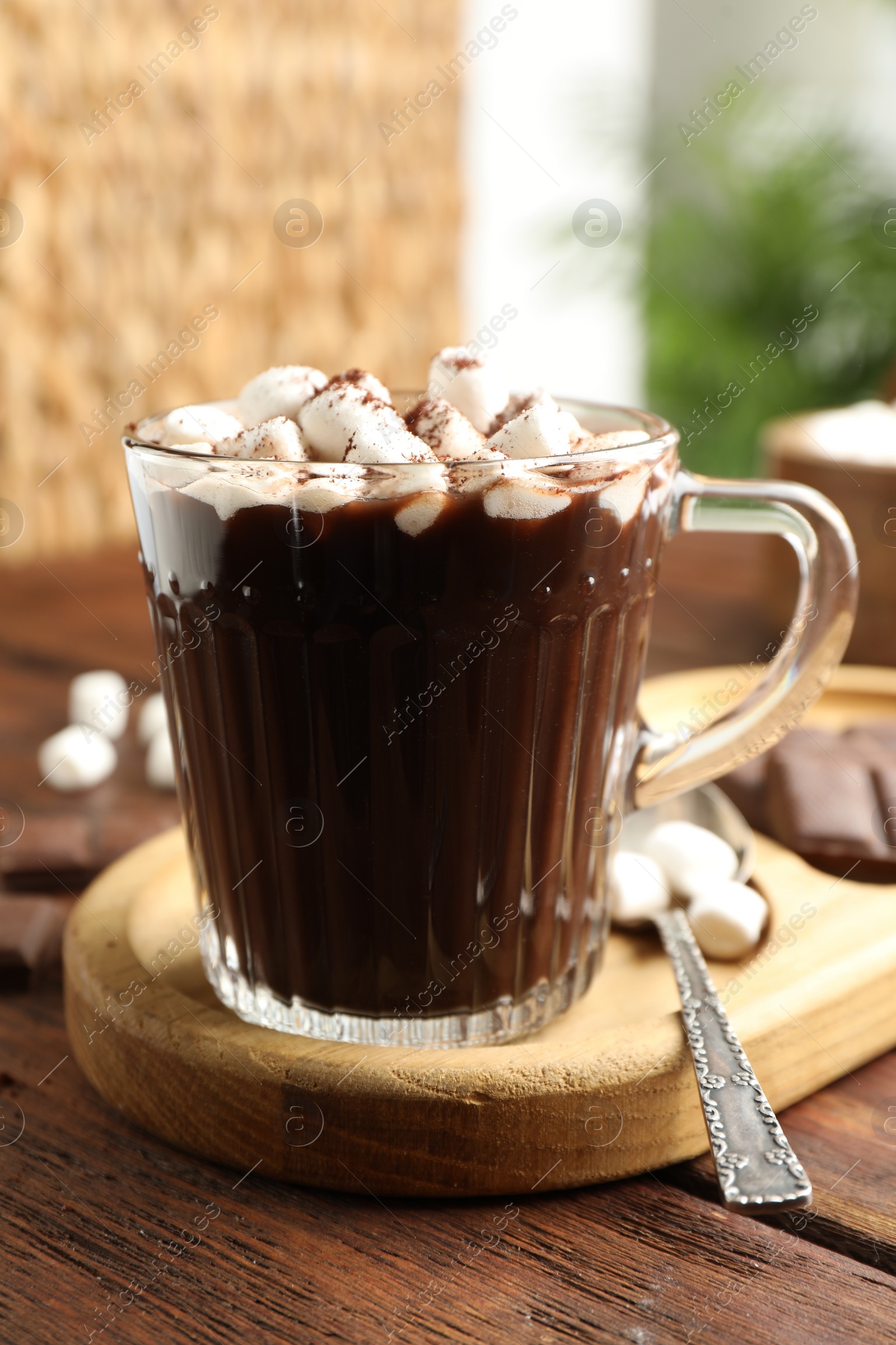 Photo of Cup of aromatic hot chocolate with marshmallows and cocoa powder served on wooden table, closeup