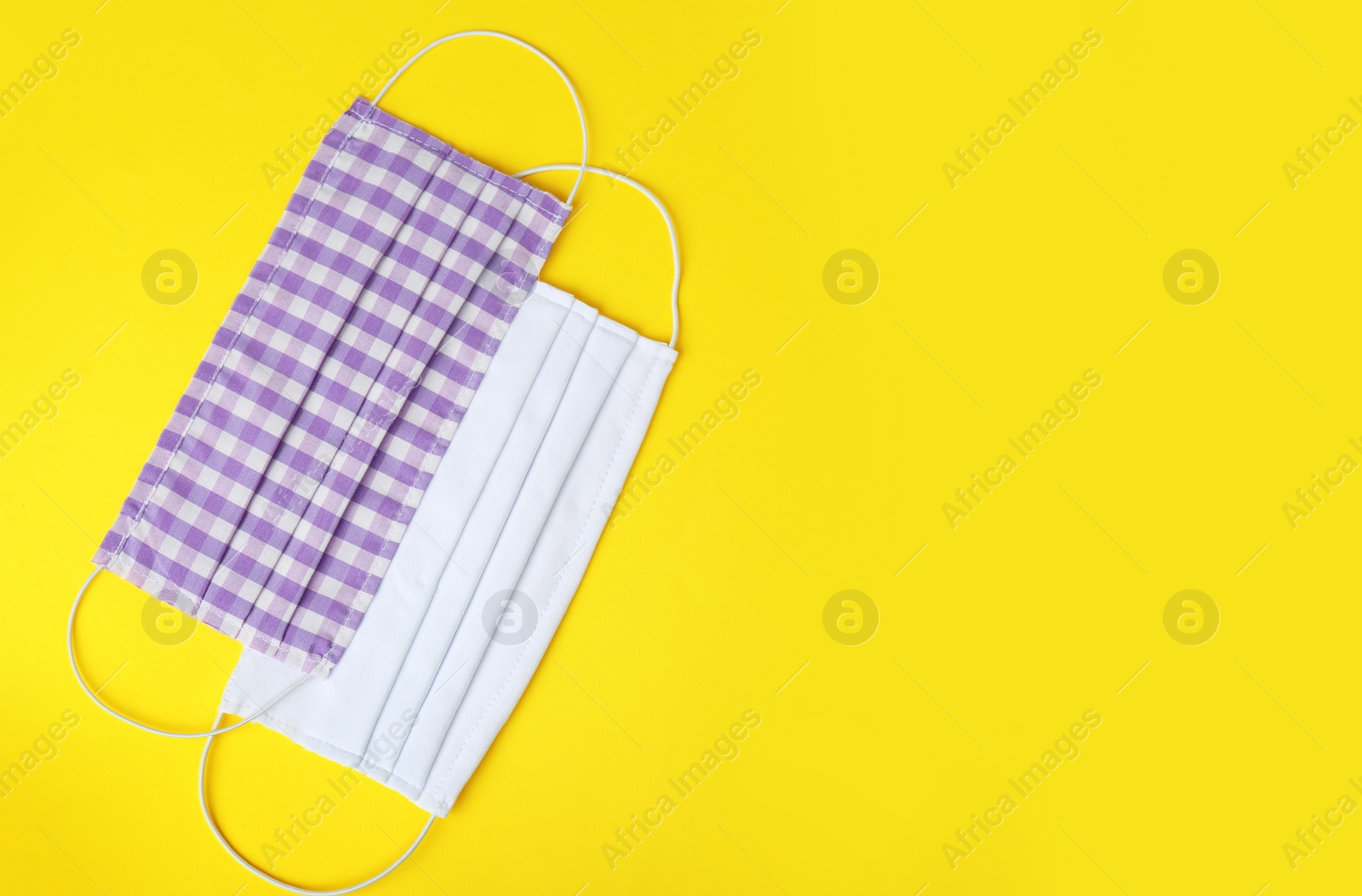 Photo of Homemade protective face masks on yellow background, flat lay. Space for text