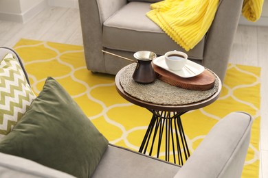 Photo of Cup of coffee and cezve on table in living room