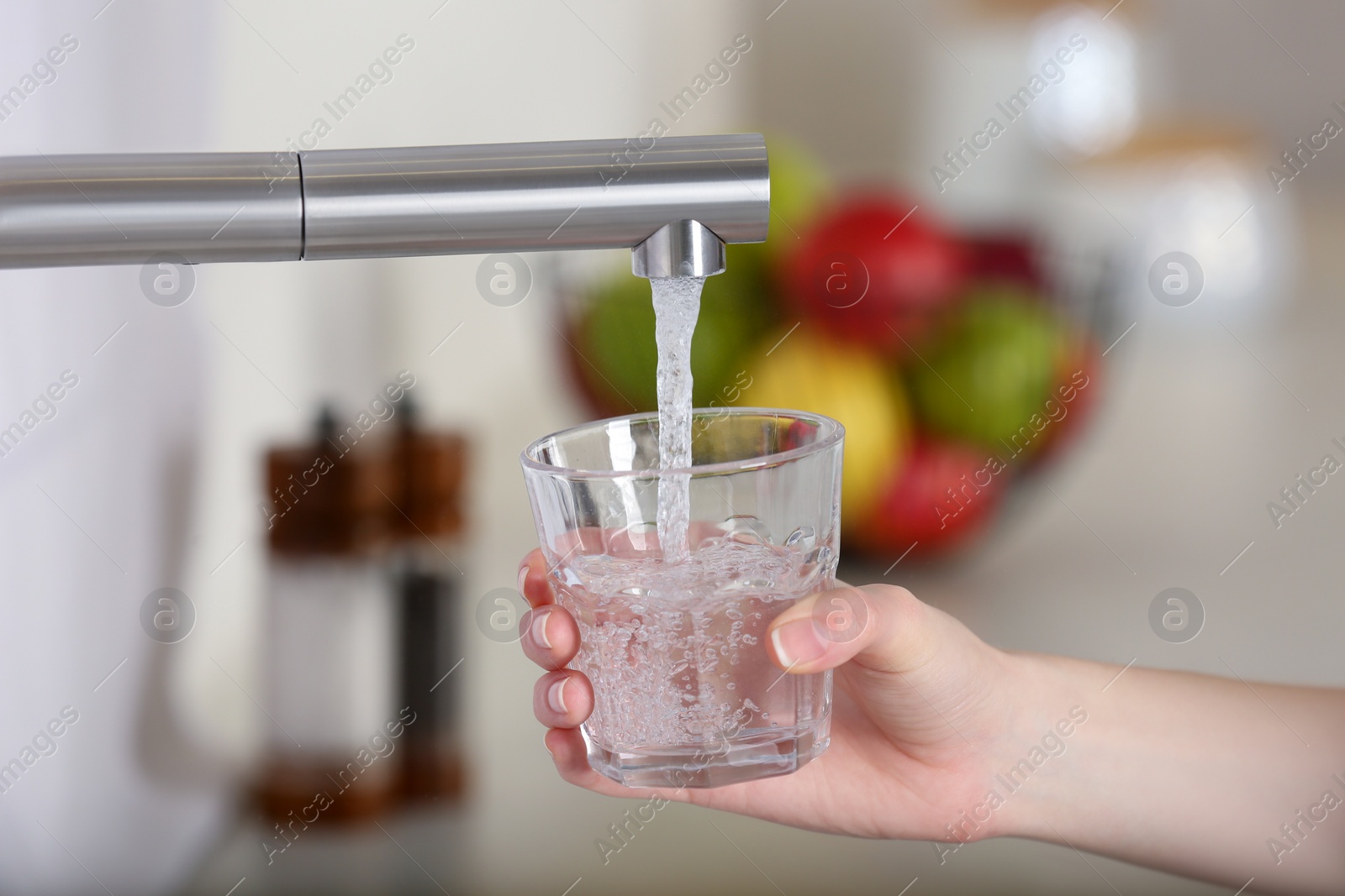 Photo of Woman filling glass with tap water from faucet in kitchen, closeup