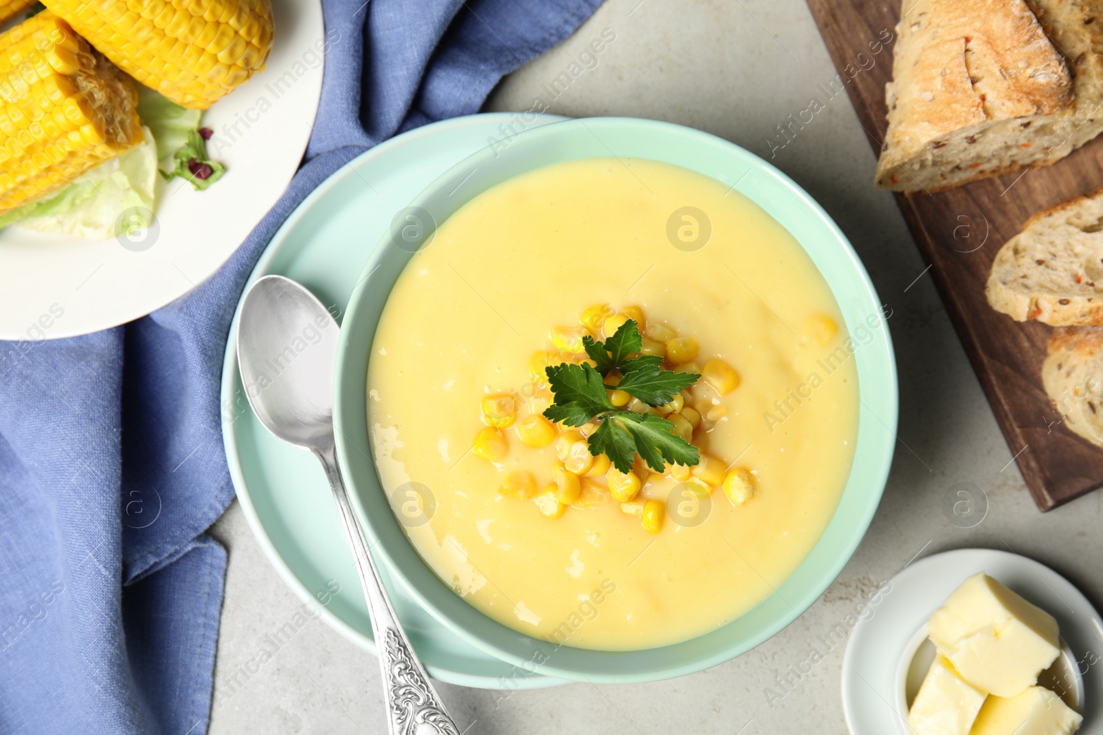 Photo of Delicious corn cream soup served on light grey table, flat lay