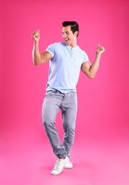 Photo of Handsome young man dancing on pink background