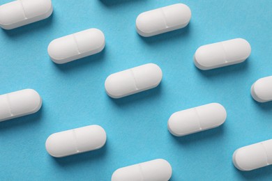 White pills on light blue background, flat lay