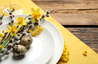 Festive Easter table setting with quail eggs and floral decor on wooden background, closeup