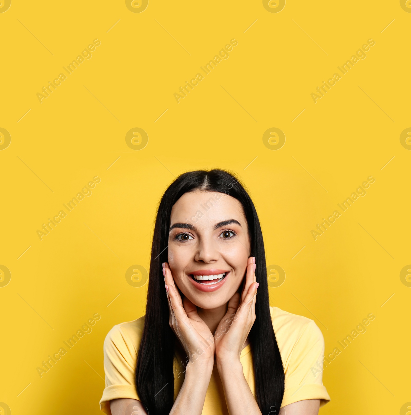 Photo of Portrait of happy young woman with beautiful black hair and charming smile on yellow background