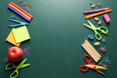 Flat lay composition with scissors and school supplies on chalkboard. Space for text