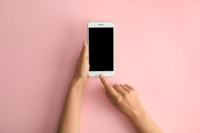 Photo of Woman holding modern phone on pink background, top view. Space for text