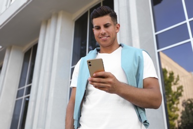 Photo of Handsome man using modern mobile phone outdoors